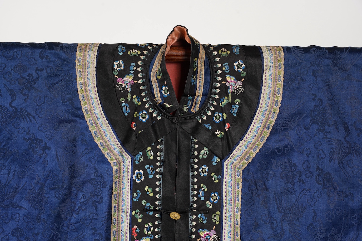 A late 19th century Chinese blue silk damask jacket, woven with Phoenix and auspicious symbols. The jacket edged with ornate rows of braiding and silk embroidery, the interior with original pink silk lining. The jacket f